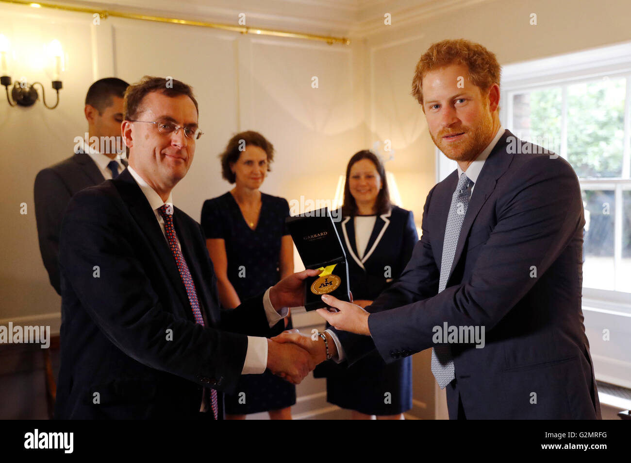 Il principe Harry (destra) con le mani su un Invictus Games medaglia d'oro conquistata da Elizabeth Segna per il consulente intensivist Dr Alain Vuylsteke, originariamente provenienti dal Belgio e gli altri membri del Papworth Hospital Medical team che ha contribuito a salvare il servicewoman la vita, come essi visitare Kensington Palace a Londra. Foto Stock