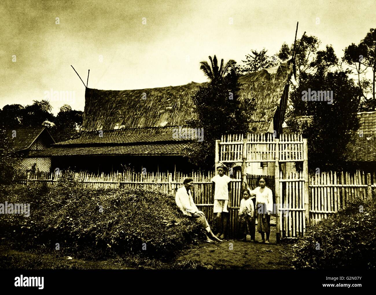 La fotografia mostra un gruppo gli abitanti del villaggio si fermò al di fuori di un recintata village. Le Indie orientali olandesi, noto come Indonesia moderna. Datata c1935. Foto Stock