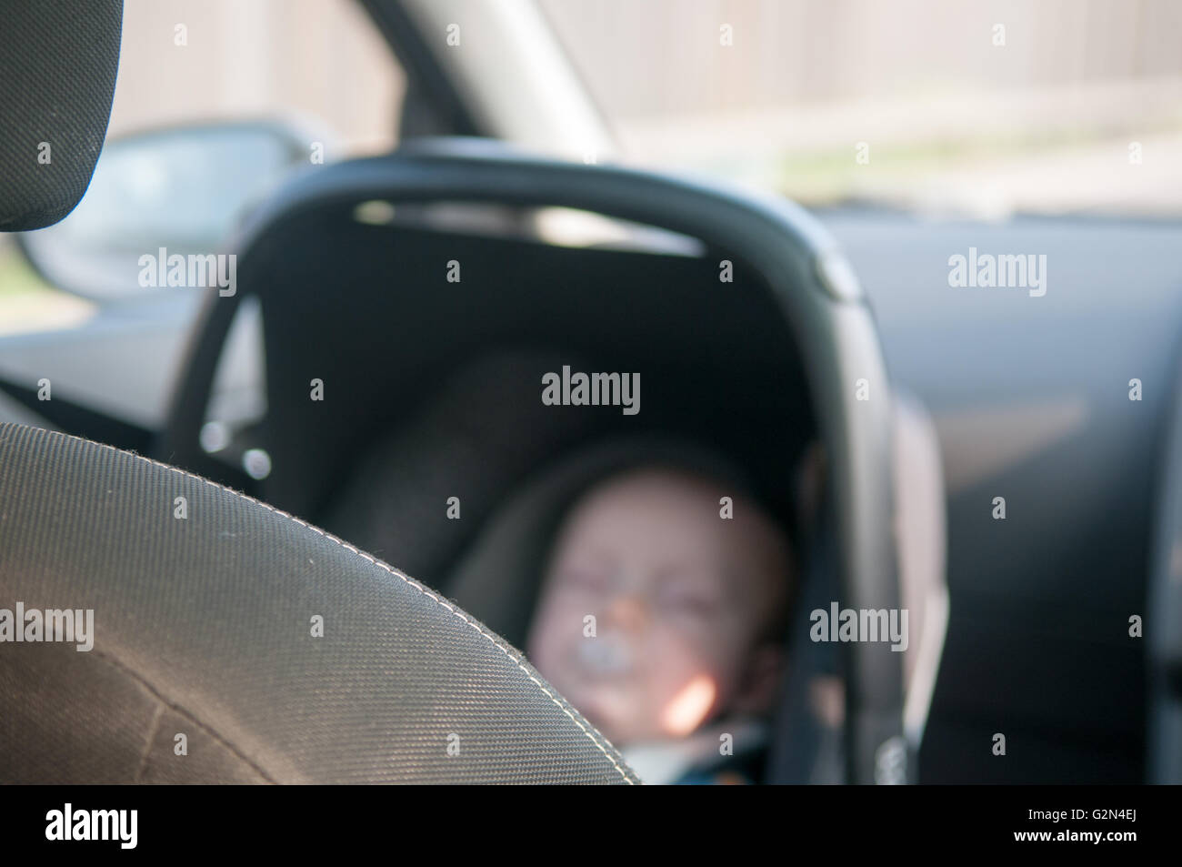 Bambino nella parte posteriore rivolta verso il sedile auto viaggiare in modo sicuro su un viaggio Foto Stock