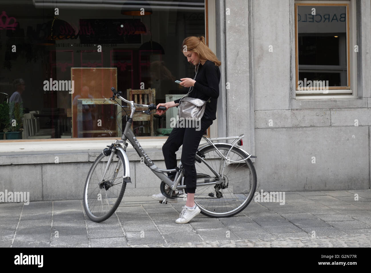 Ragazza controllando il suo telefono ad Anversa in Belgio in Europa Foto Stock
