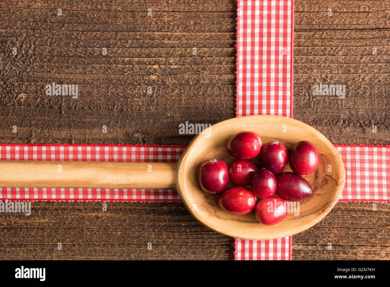 Sfondo rustico con mirtilli rossi su un cucchiaio di legno. Foto Stock