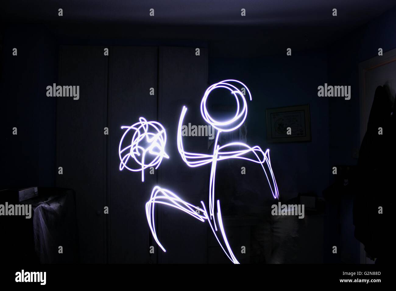 Una lunga esposizione colpo di luce disegnando su una stick persona facendo keep ups con una sfera Foto Stock