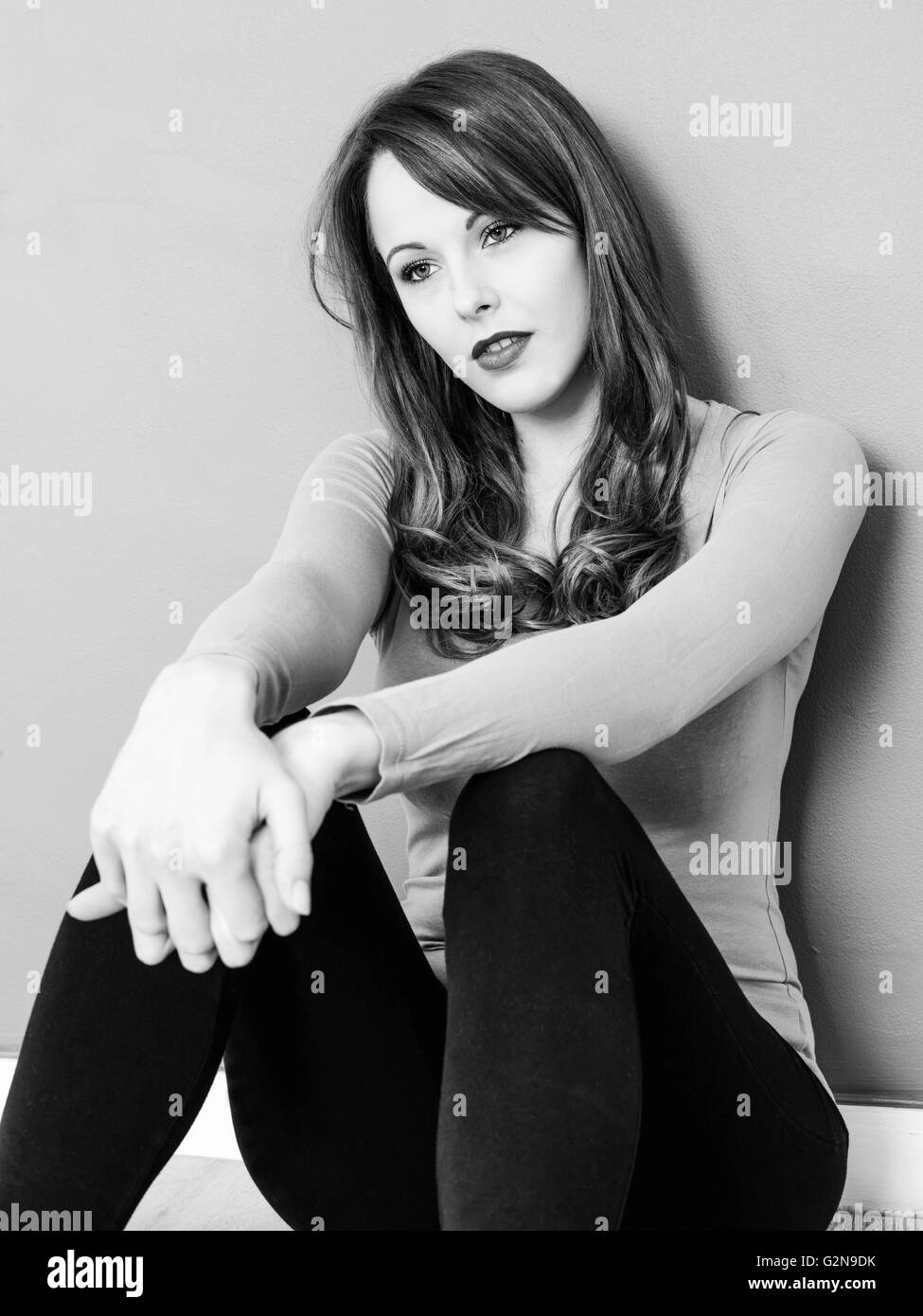 Ritratto di un triste premuto Lonely giovane donna seduta sul pavimento in un umore pensieroso giorno sognare del passato Foto Stock