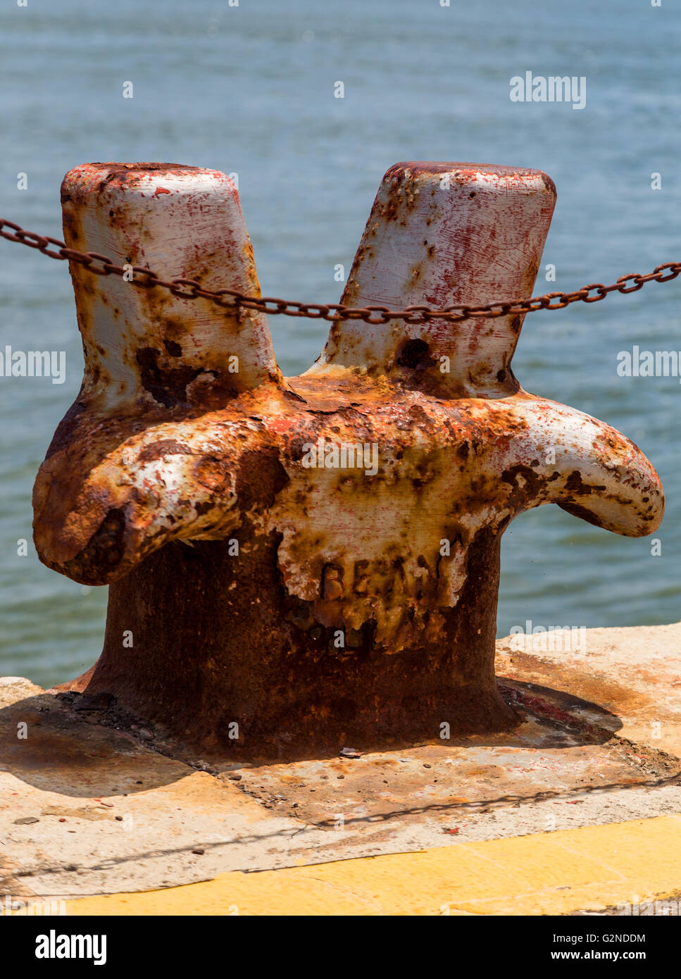 Grande vecchio metallo arrugginito bollard in marine con catena Foto Stock
