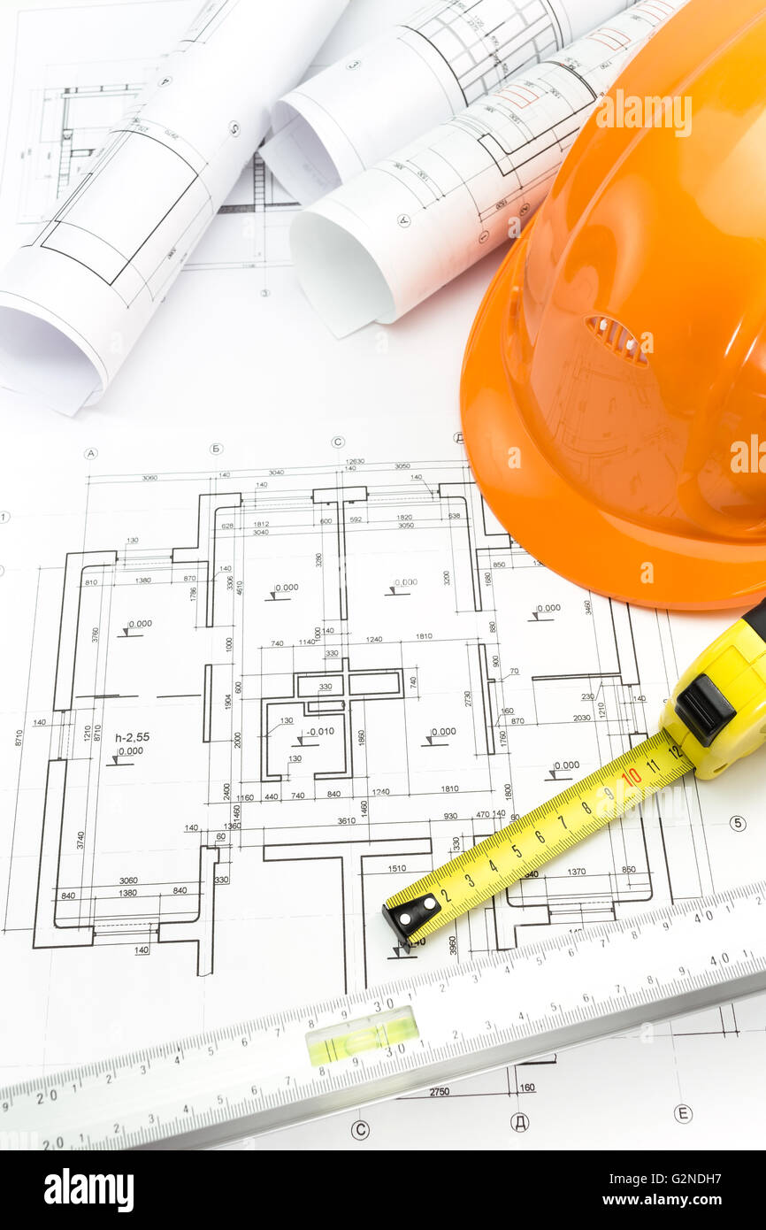 Casco di sicurezza a nastro e strumenti di misurazione su disegni di architettura Foto Stock