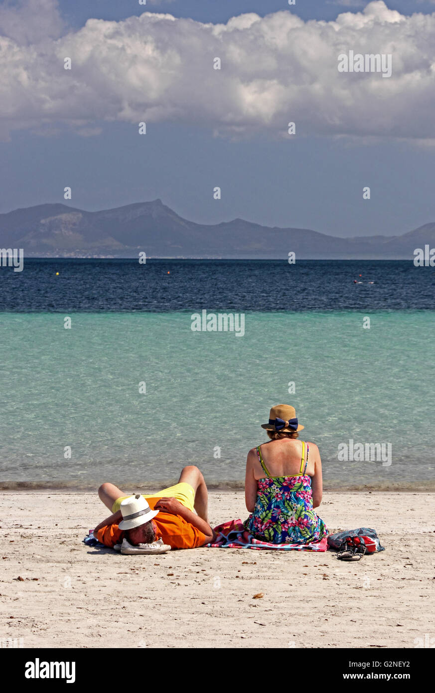 Coppia di mezza età seduti sulla spiaggia di Alcudia, Mallorca Foto Stock