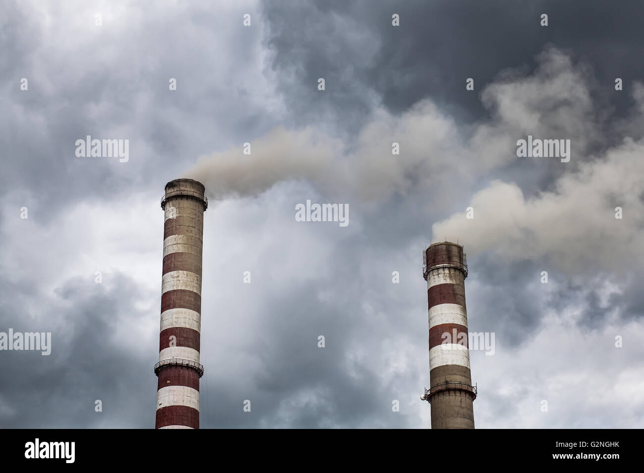 Il fumo grandi camini industriali in nuvole scure. Concetto per la tutela ambientale Foto Stock