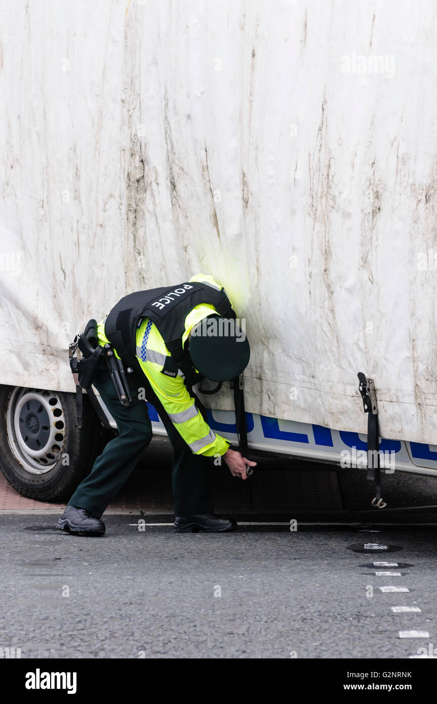 Belfast 29/09/2012 - PSNI funzionario di polizia i legami verso il basso un schermo mobile a lato di un veicolo di polizia. Gli schermi sono utilizzati in Irlanda del Nord per separare i due lati della comunità durante gli eventi sensibili come le parate e dimostrazioni. Foto Stock