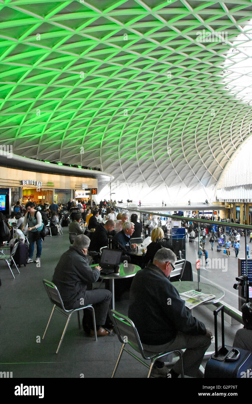Stazione dei treni di Kings Cross Londra tavoli e posti a sedere per cafe gli utenti sul piano ammezzato interno atrio partenze con il verde delle luci sul soffitto England Regno Unito Foto Stock
