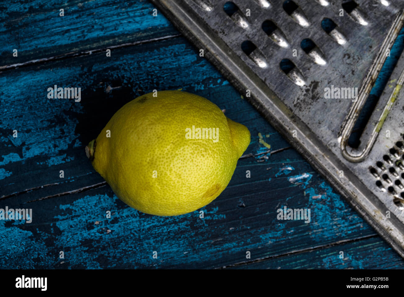 Limone fresco con metallo grattugia sulla scheda blu Foto Stock