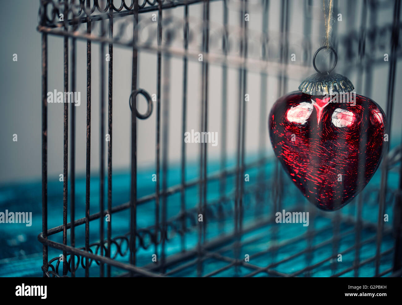 Cuore rosso intrappolato all'interno di un vecchio arrugginito gabbia per uccelli Foto Stock