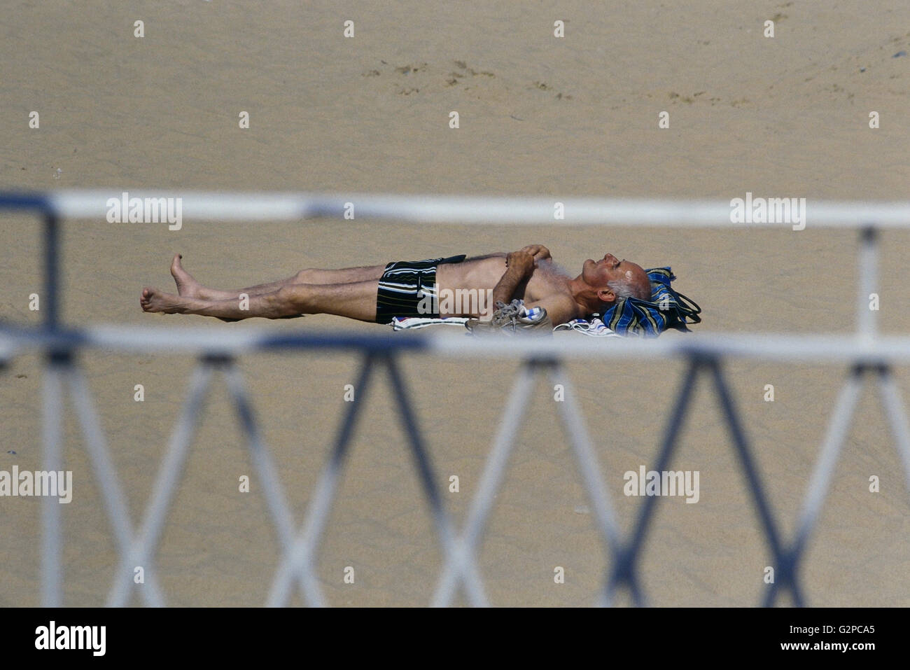 Un uomo maturo a prendere il sole su una spiaggia britannico. Regno Unito Foto Stock