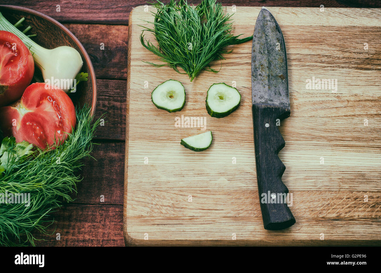 Pomodoro e divertente faccia di fette di cetriolo per insalata su di un tavolo di legno, retrò Foto Stock