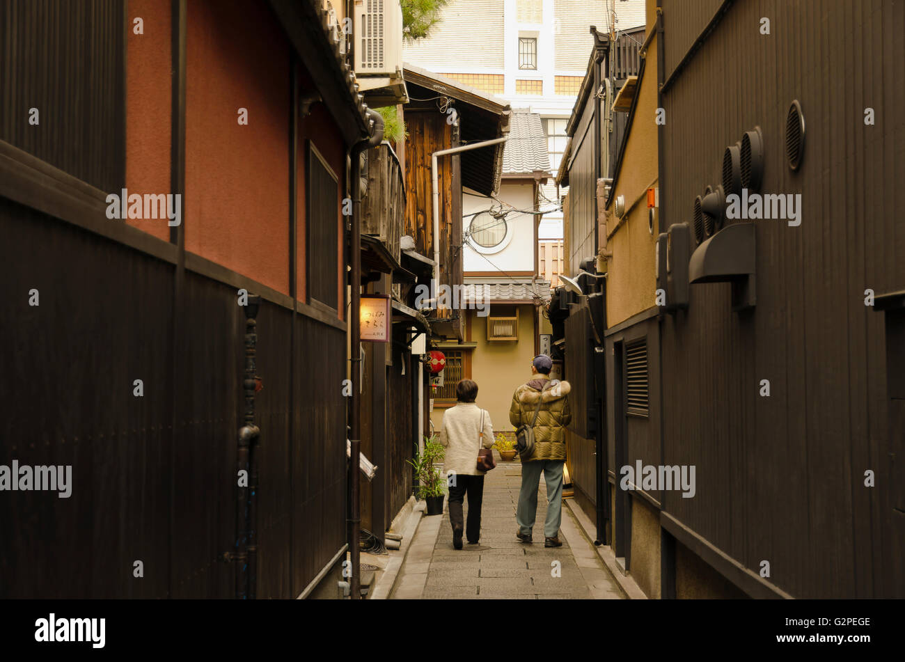 Giappone, Kyoto, edifici di stile tradizionale in area di Gion, giovane cammina verso il basso stretto vicolo. Foto Stock