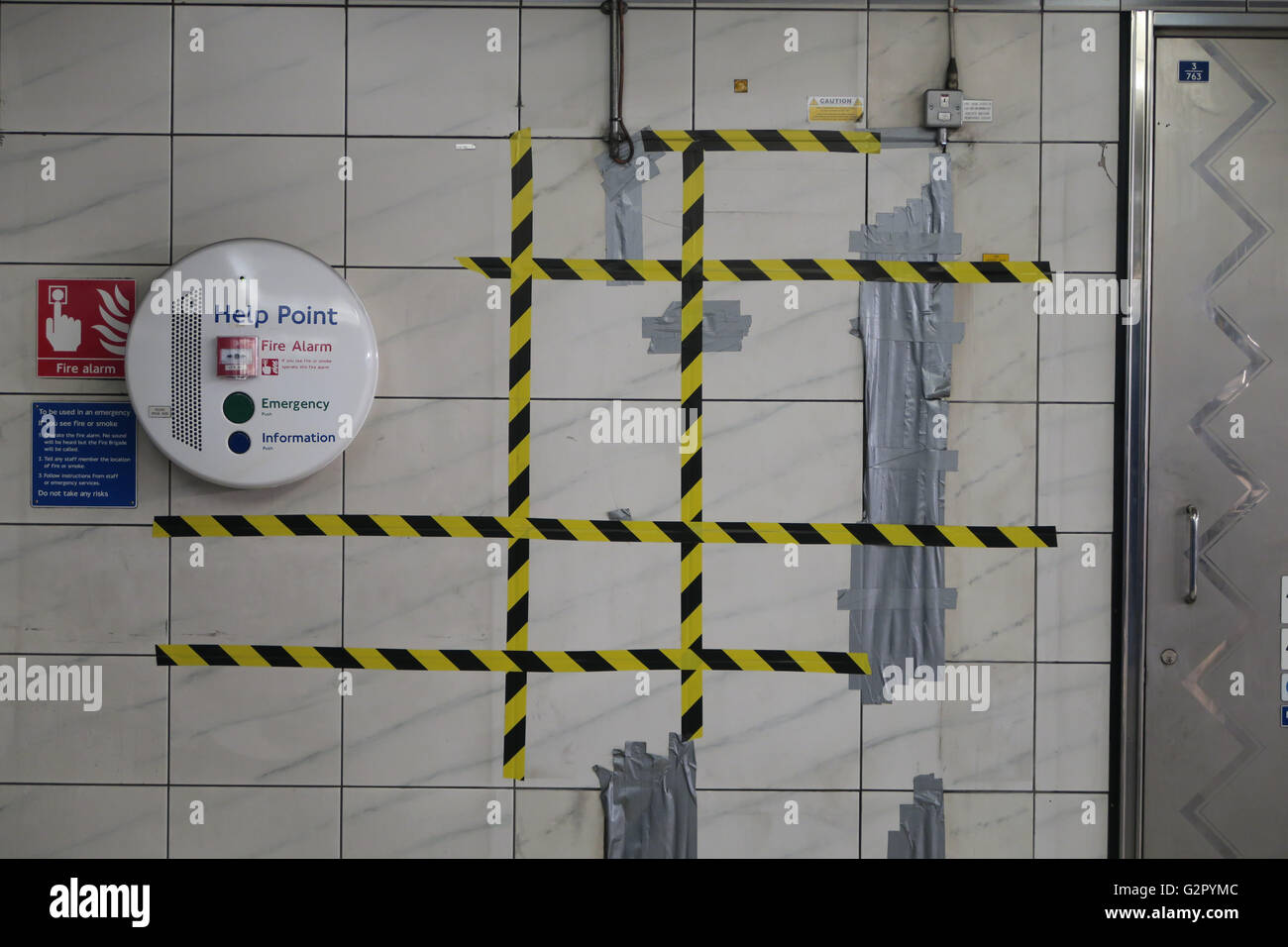 Riparazioni con nastro di avvertenza sulla metropolitana stazione di tubo a parete con piastrelle bianche, porta Foto Stock