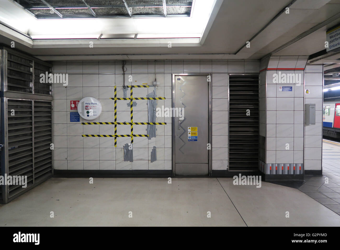 Riparazioni con nastro di avvertenza sulla metropolitana stazione di tubo a parete con piastrelle bianche, porta Foto Stock