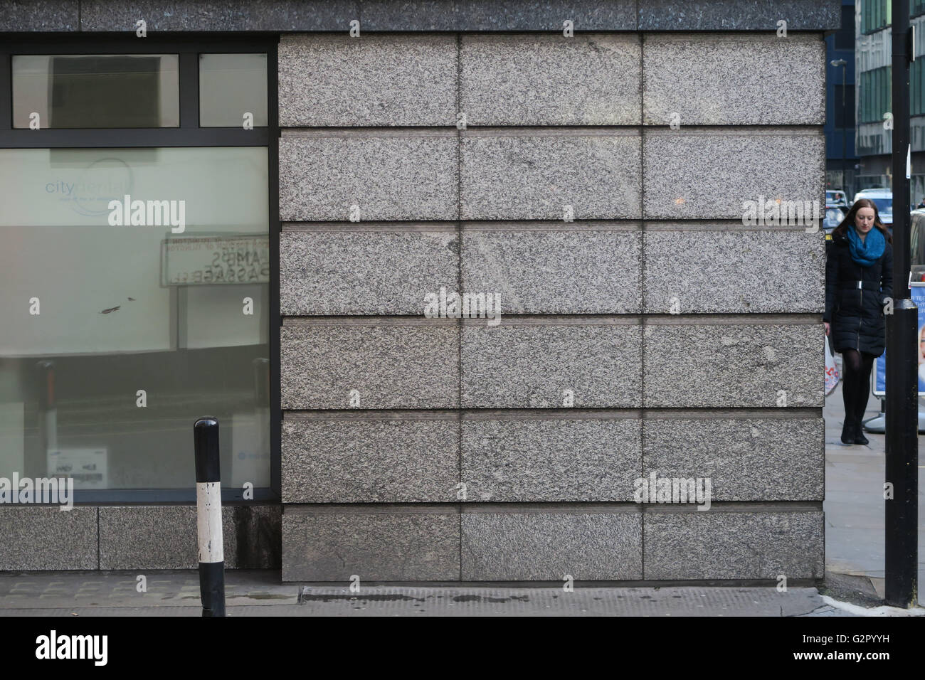 Le pareti in vetro riflettente e la donna all'angolo dell'edificio Foto Stock