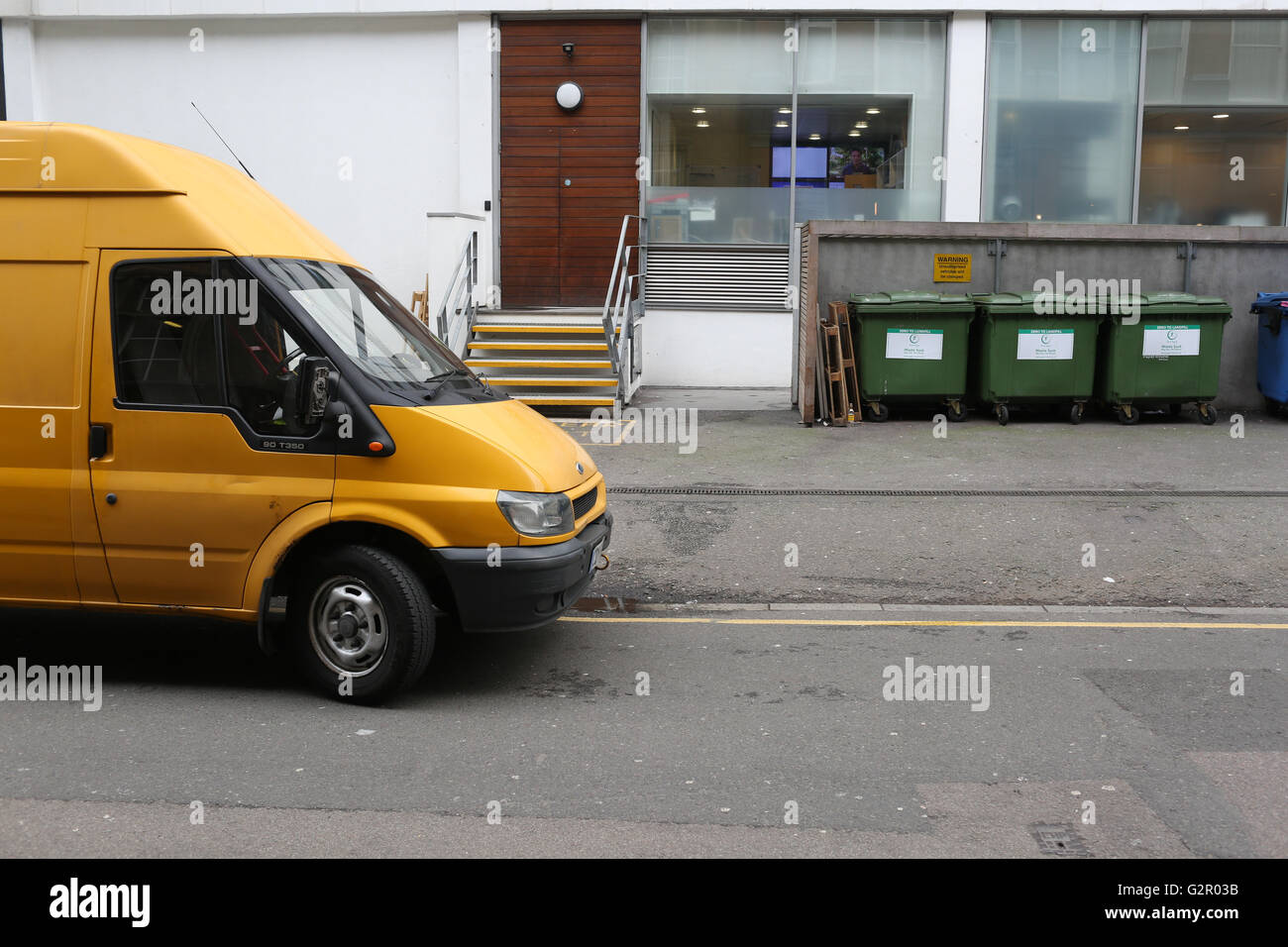 Giallo Ford Transit van parcheggiato al di fuori dei locali commerciali, cassonetti nella zona di Hammersmith London Foto Stock