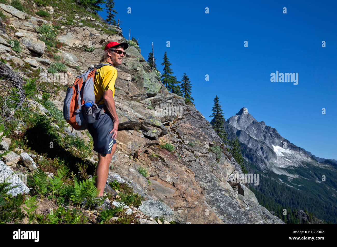 WASHINGTON - escursionista Ira ascendente Spring Mountain in vista dell'ghiacciate Pugh Montagne in Mt Baker-Snoqualmie National Forest Foto Stock