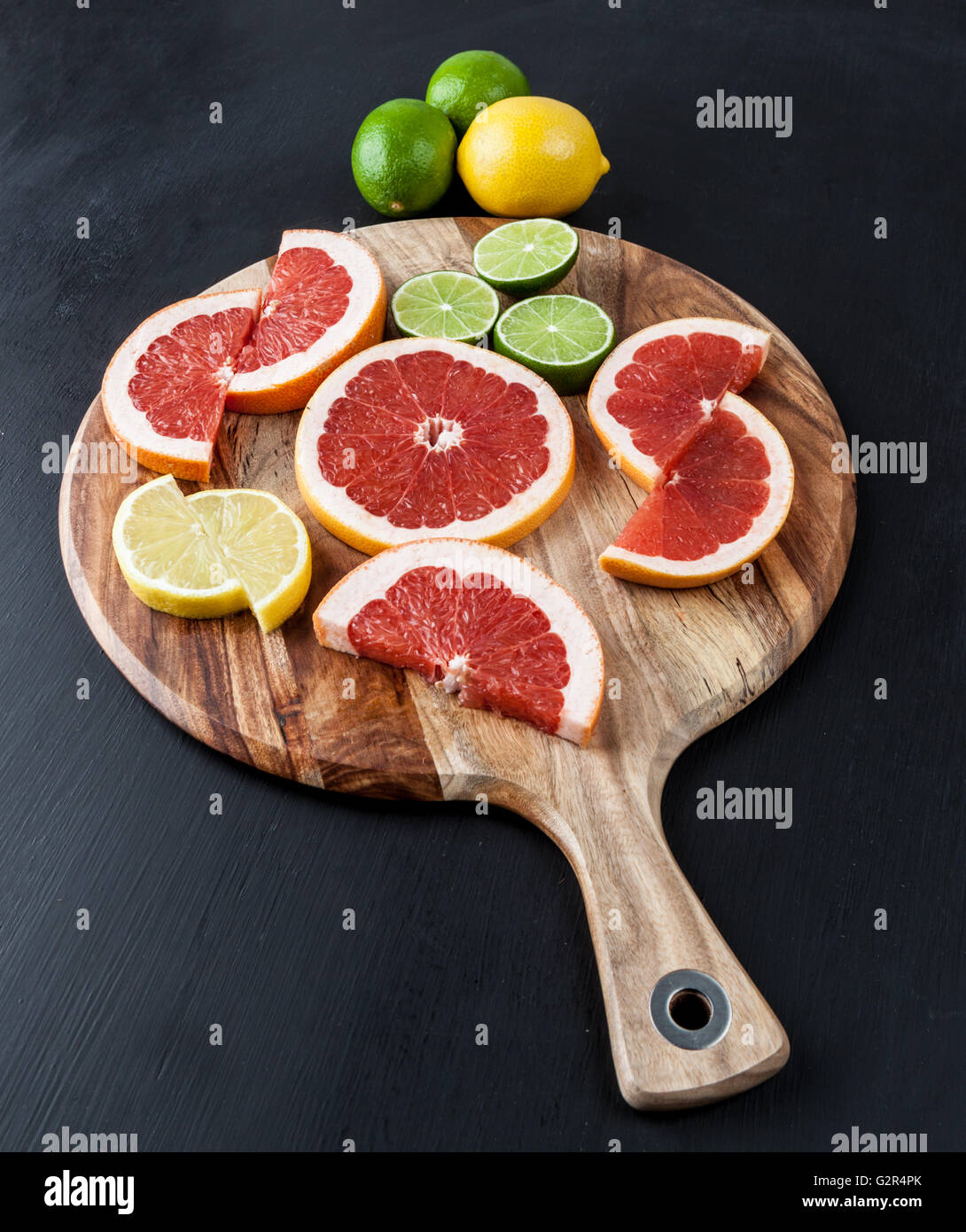 Fette di pompelmo rosso, limone, e calce di acacia tagliere. L'immagine verticale con spazio di copia Foto Stock