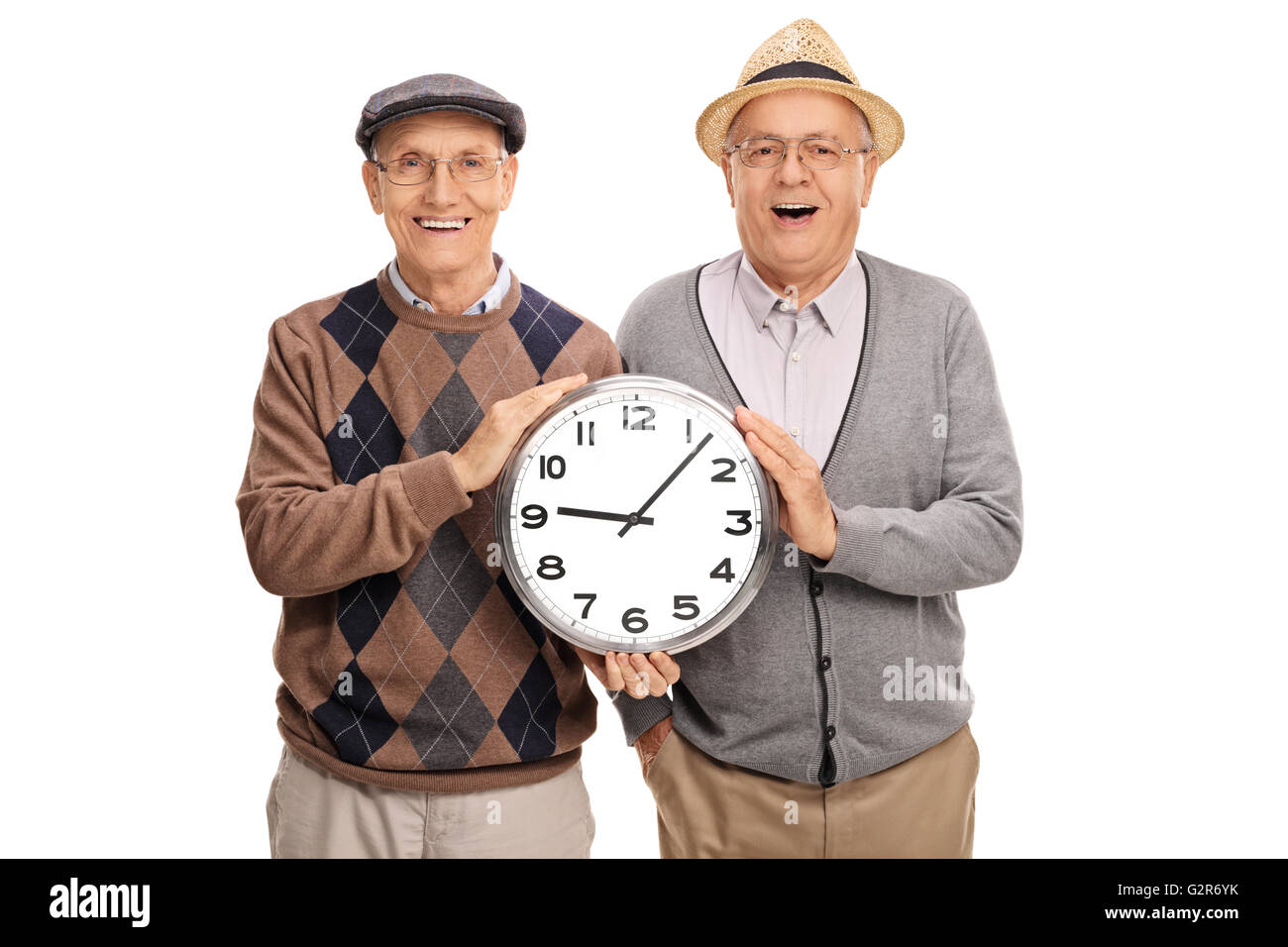 Due allegri uomini anziani tenendo un grande orologio e guardando la telecamera isolata su sfondo bianco Foto Stock