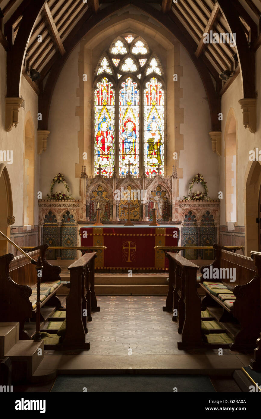 Vista interna della Chiesa della Santa Trinità, un villaggio inglese chiesa, cercando la navata verso l altare con una finestra di vetro colorato Foto Stock