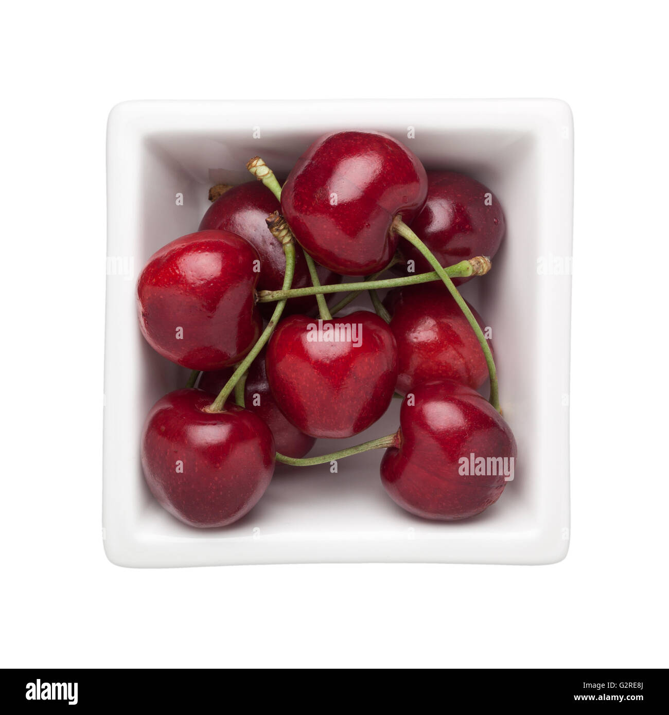 Le ciliegie in un recipiente quadrato isolato su sfondo bianco Foto Stock