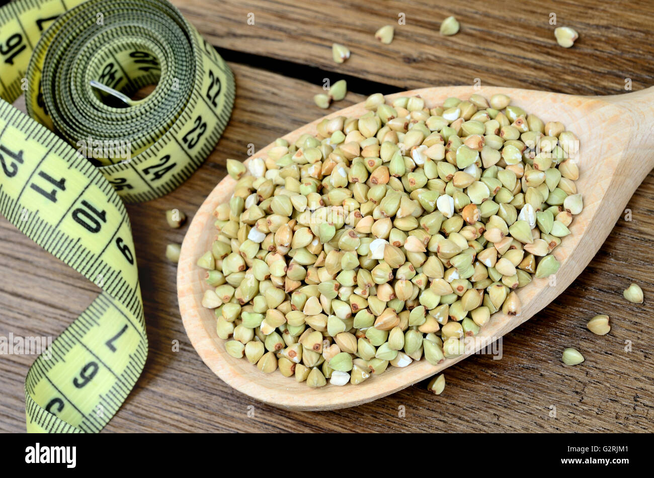 Il verde del grano saraceno in un cucchiaio di legno e centimetro su tavola Foto Stock
