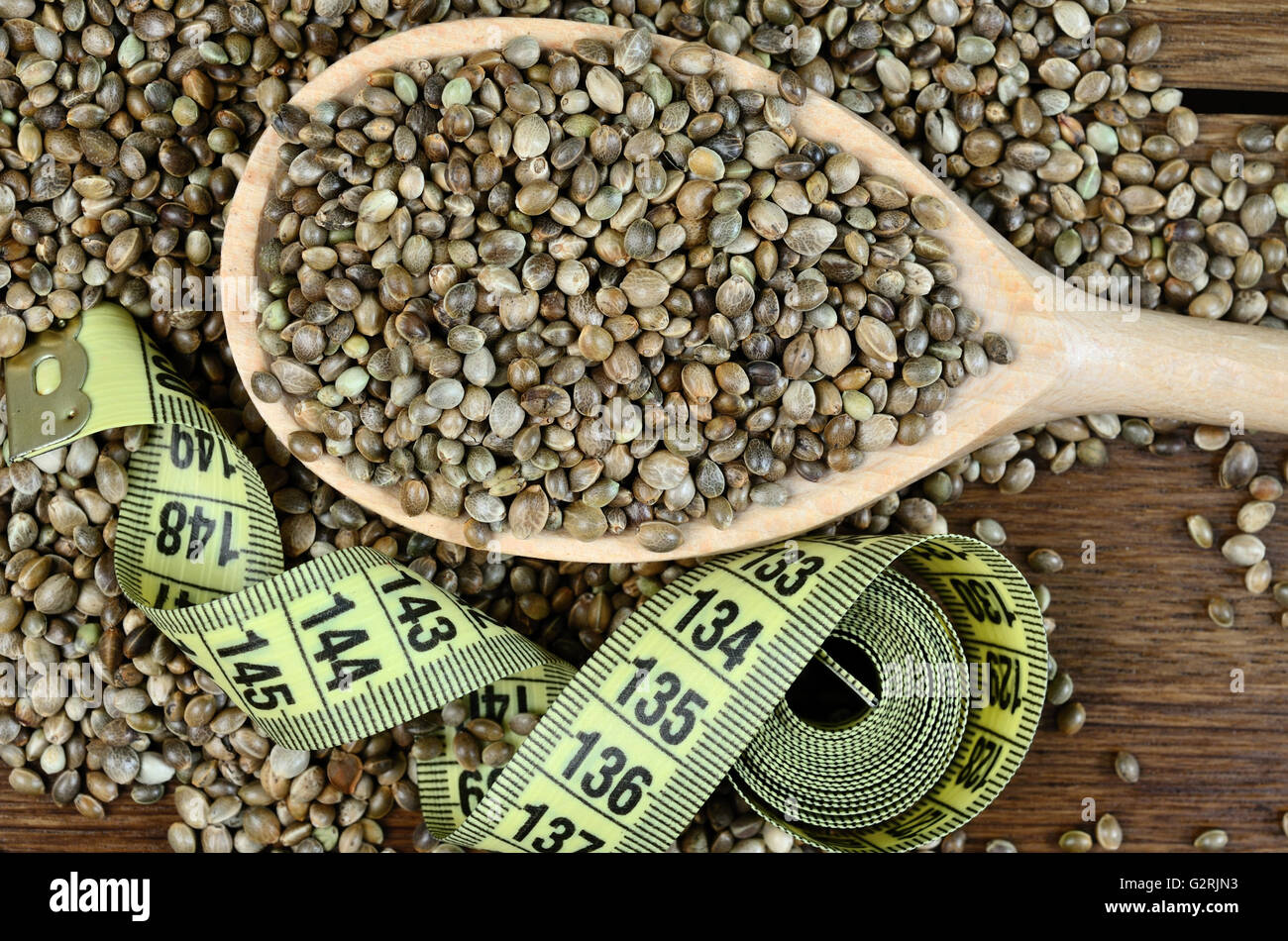 Sana di semi di canapa in un cucchiaio di legno con il centimetro sul tavolo Foto Stock