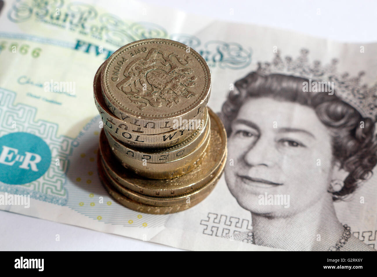 British cinque libbra banconota e la pila di libbra di monete Foto Stock