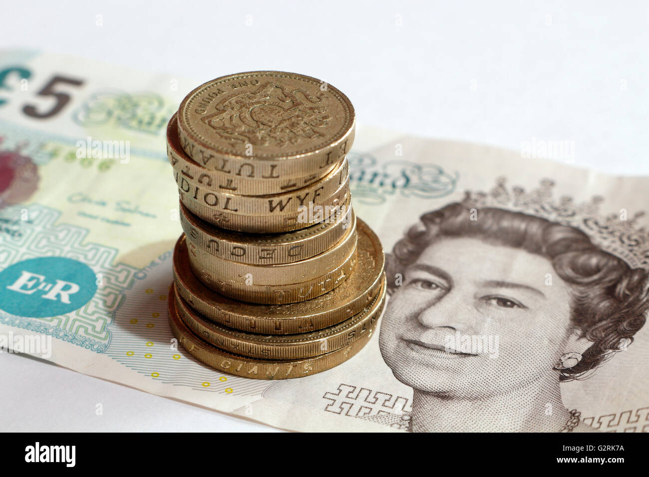 British cinque libbra banconota e la pila di libbra di monete Foto Stock
