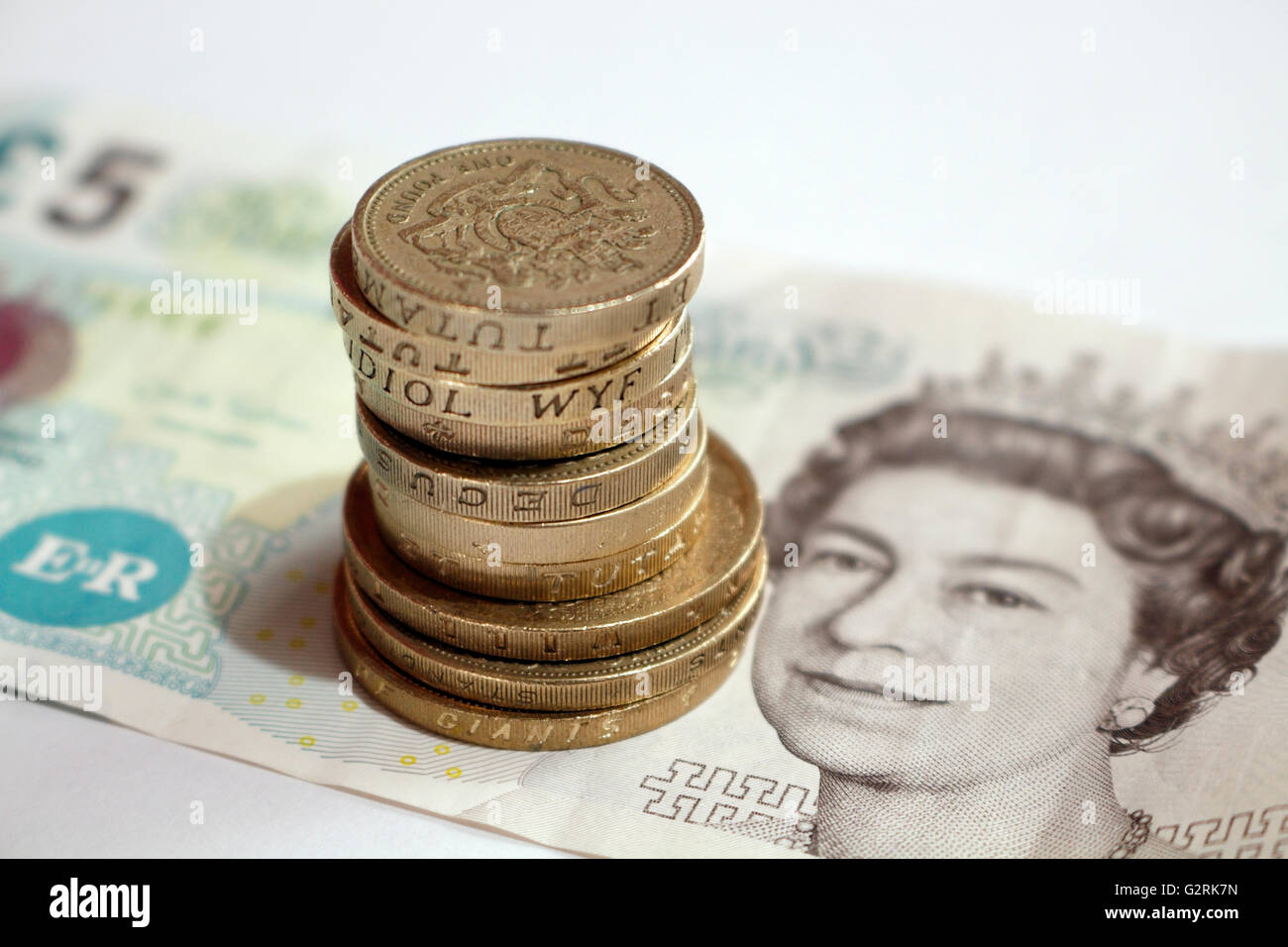 British cinque libbra banconota e la pila di libbra di monete Foto Stock