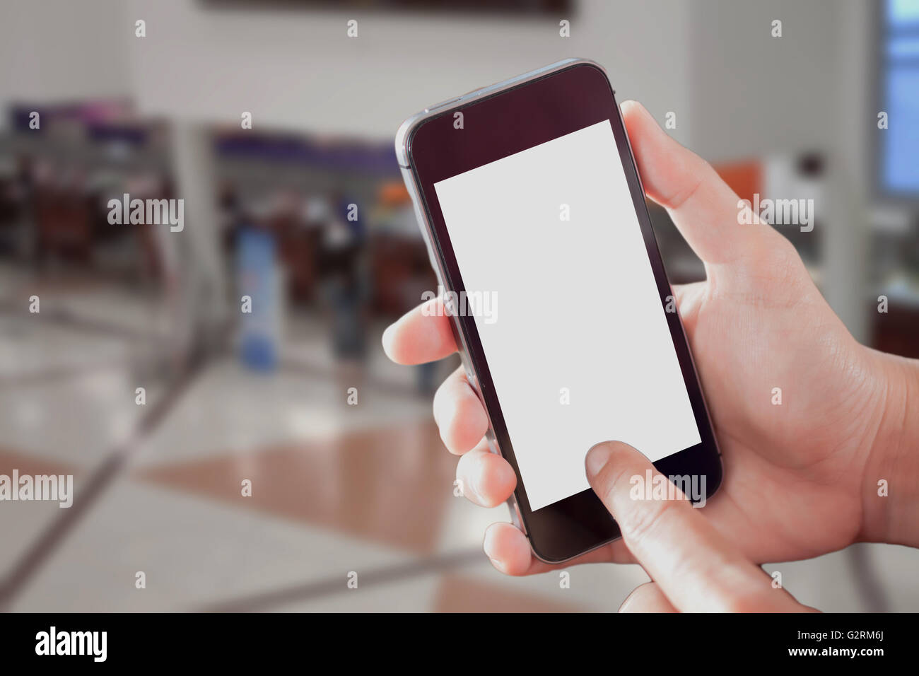 Smart Phone con schermo bianco in mano sul offuscata dall'aeroporto in background Foto Stock