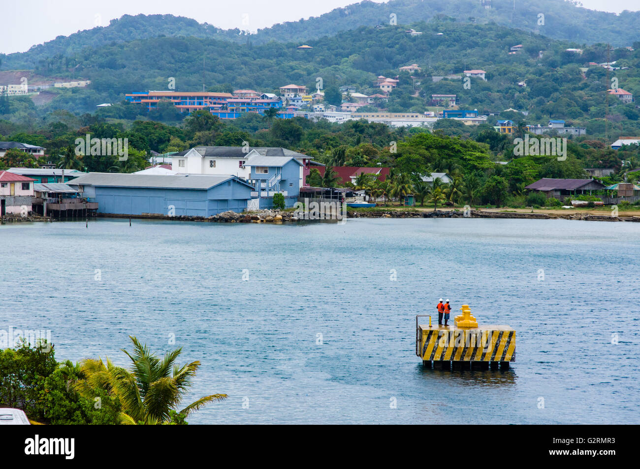 Due lavoratori in attesa su un molo per una nave da crociera al dock. Roatan, Honduras Foto Stock