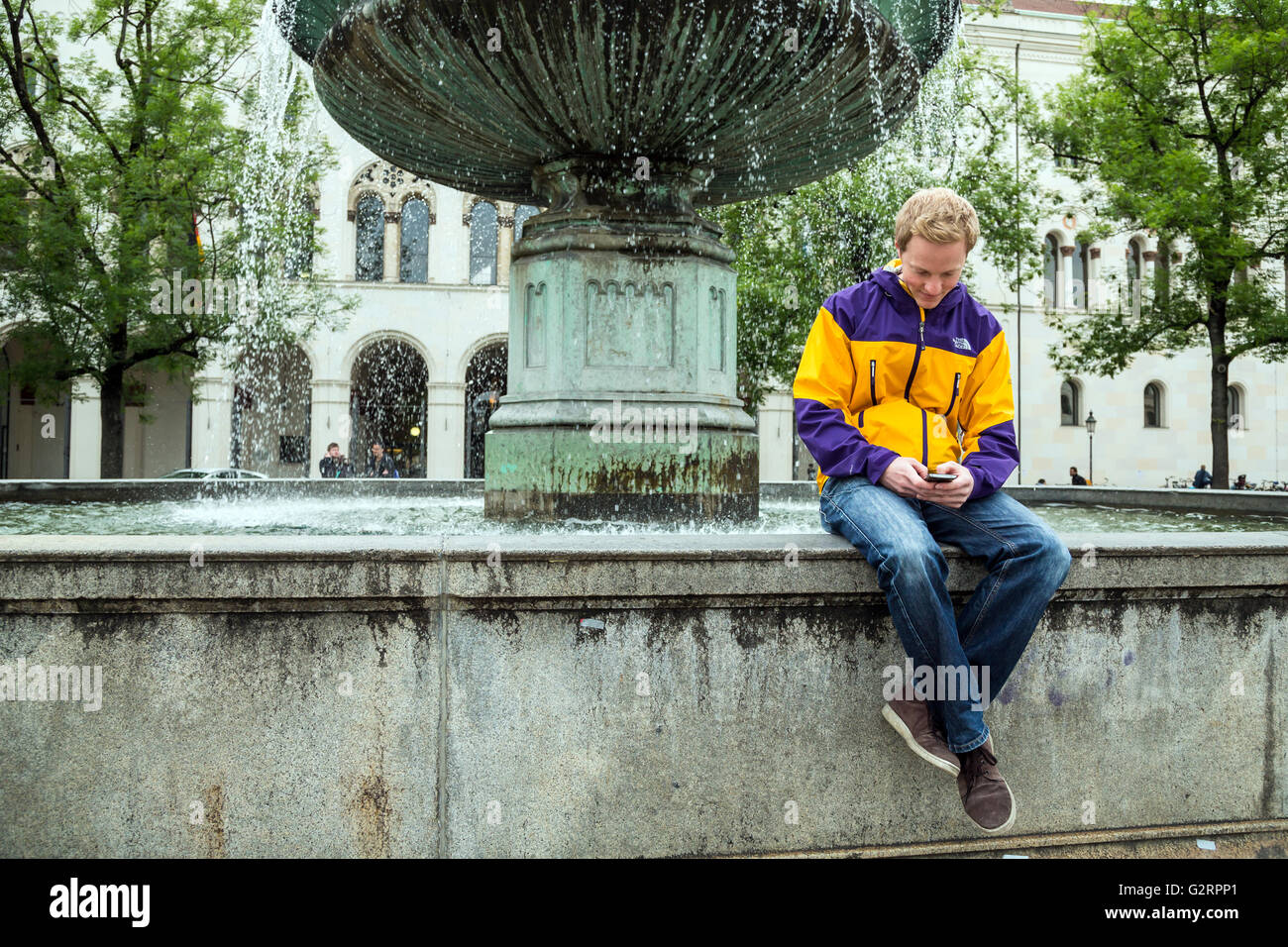 Muenchen, Germania, studente seduto da fontana sulla Geschwister-Scholl-Platz Foto Stock