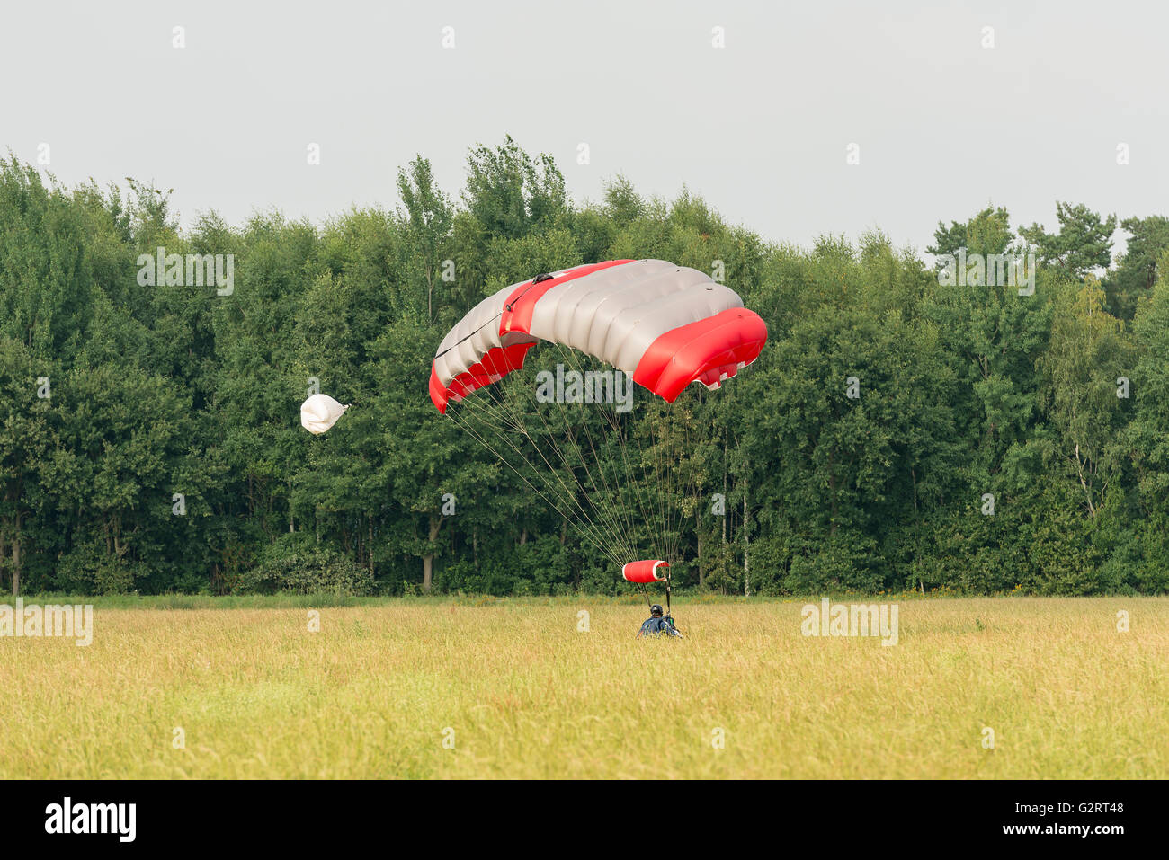Un Just Landed parachutist con un materasso di paracadute sagomato in un campo Foto Stock