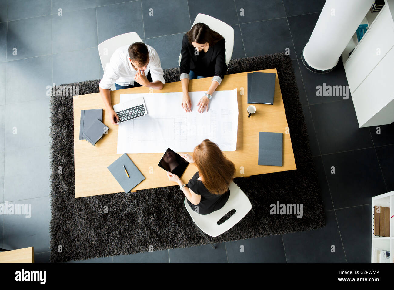 Giovani architetti seduti a tavola in ufficio Foto Stock