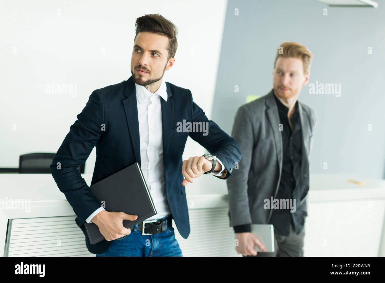 Due giovani uomini con tablet e file in uffici moderni Foto Stock
