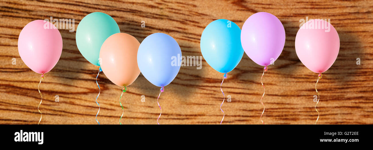 Aria variopinti palloncini volanti su sfondo di legno Foto Stock