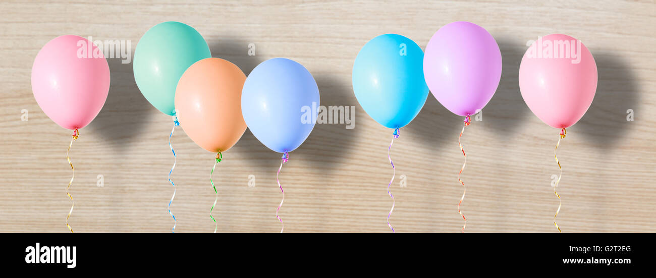 Aria variopinti palloncini volanti su sfondo di legno Foto Stock