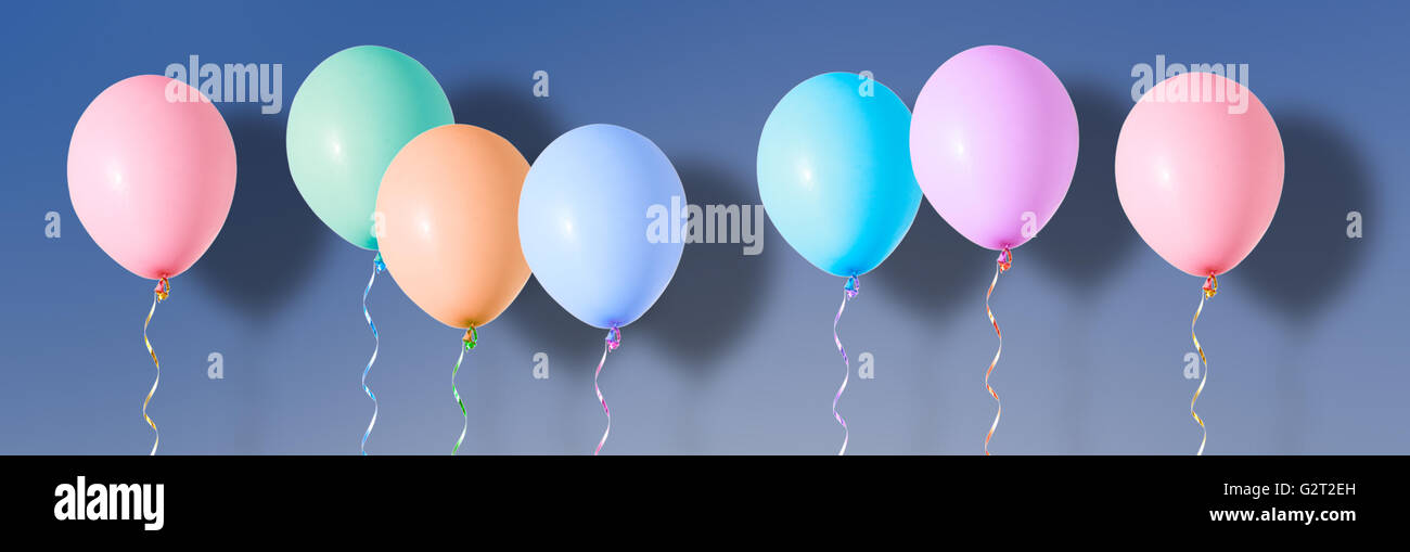 Aria variopinti palloncini volanti su sfondo blu Foto Stock