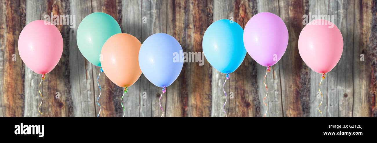 Aria variopinti palloncini volanti su sfondo di legno Foto Stock