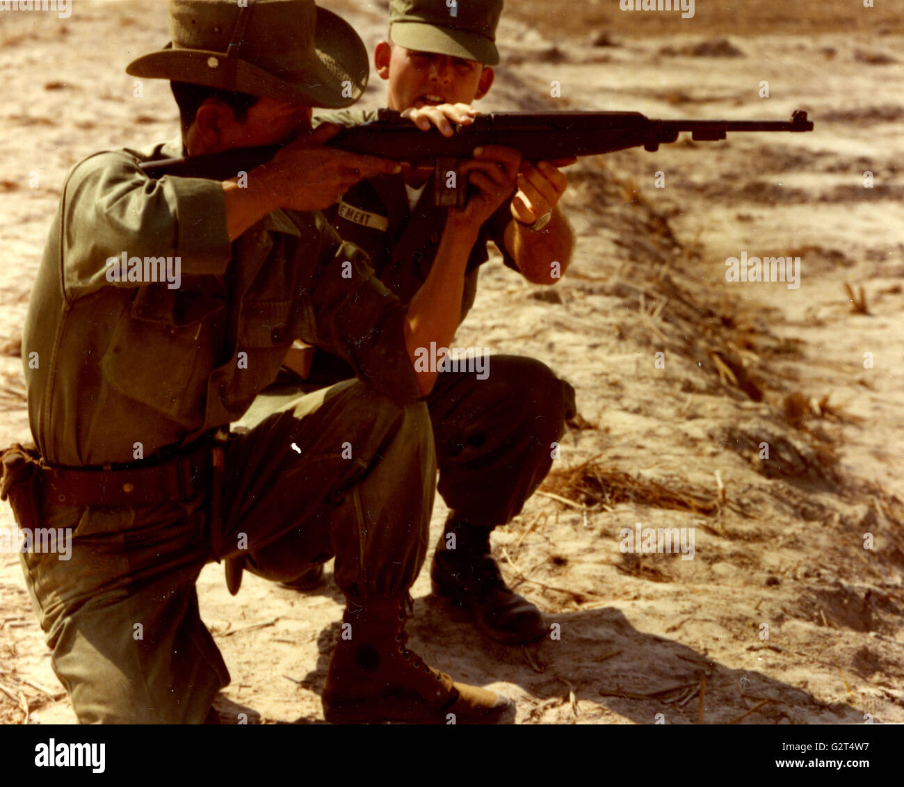 American Consigliere militare Lt. Joe Clemente (centro) dà uno del sud soldati vietnamiti lavora con poche indicazioni sul modo di migliorare la sua precisione con il M-2 carabina. Foto Stock