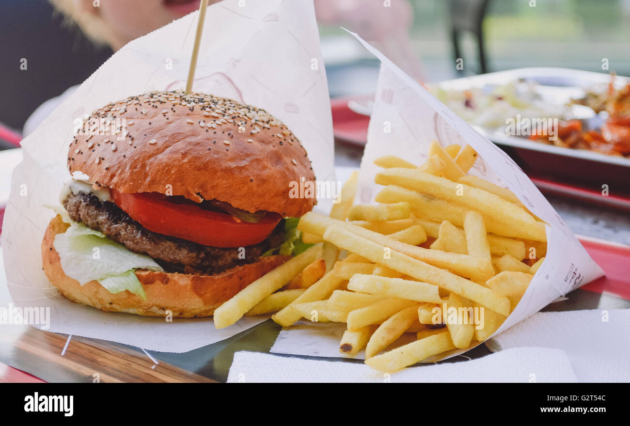 Fresh burger closeup su legno tavolo rustico con patate fritte e trucioli Foto Stock