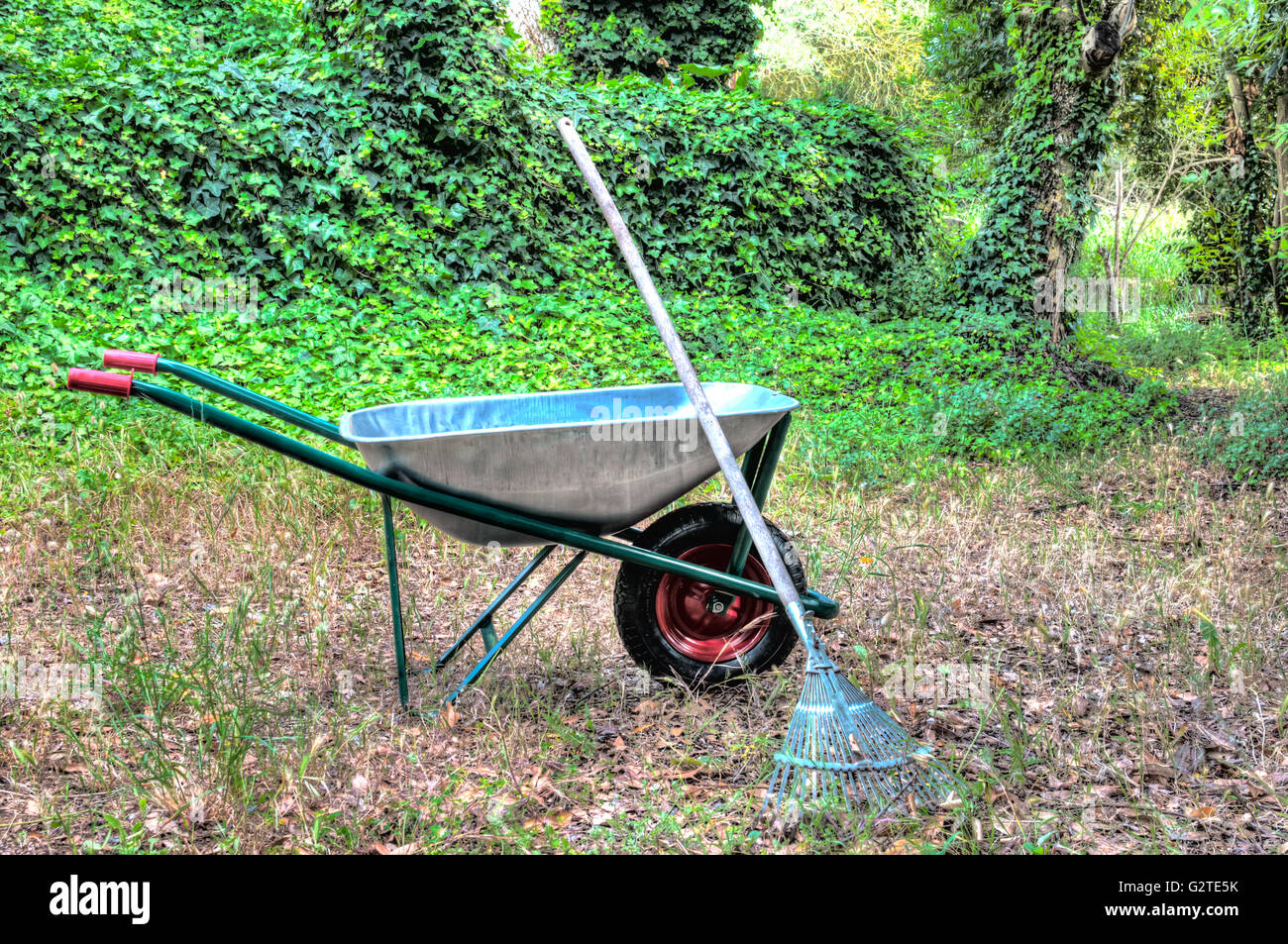 Hdr della carriola in un giardino e un rastrello Foto Stock
