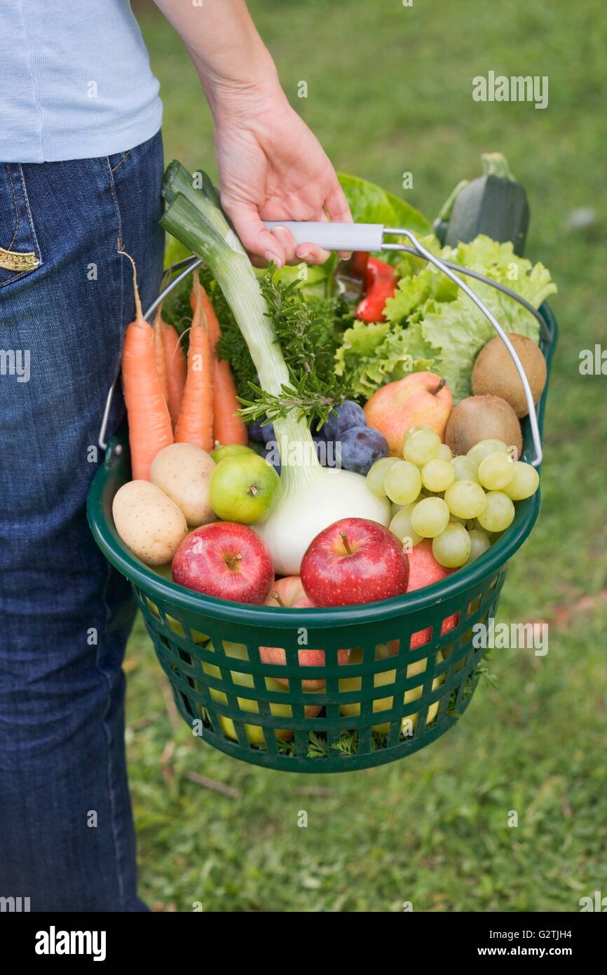 Una donna che porta un cesto di frutta e verdura Foto Stock