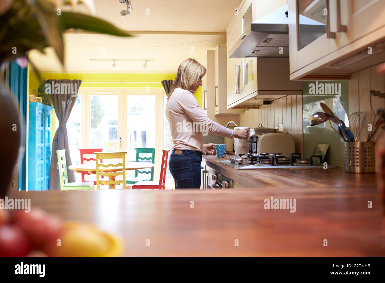 Donna riempire il bollitore in cucina di elegante appartamento Foto Stock