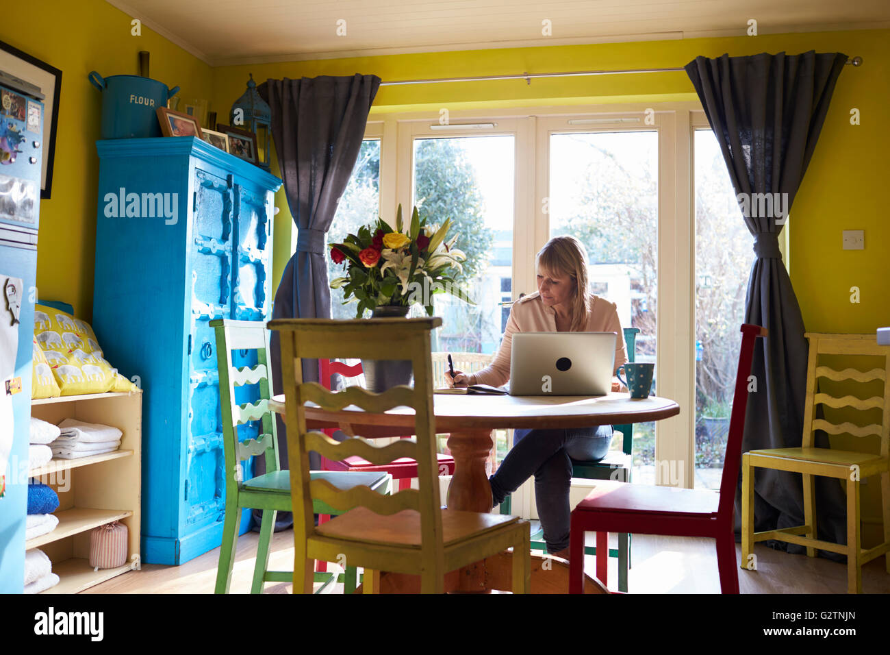Donna che utilizza computer portatile al tavolo da pranzo di elegante appartamento Foto Stock