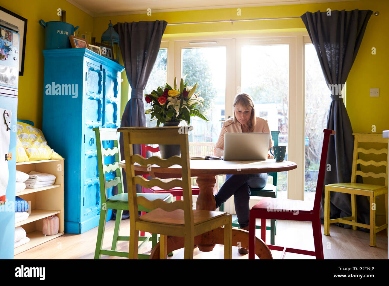 Donna che utilizza computer portatile al tavolo da pranzo di elegante appartamento Foto Stock