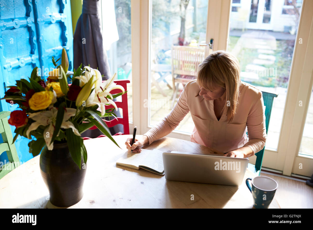Donna che utilizza computer portatile al tavolo da pranzo di elegante appartamento Foto Stock